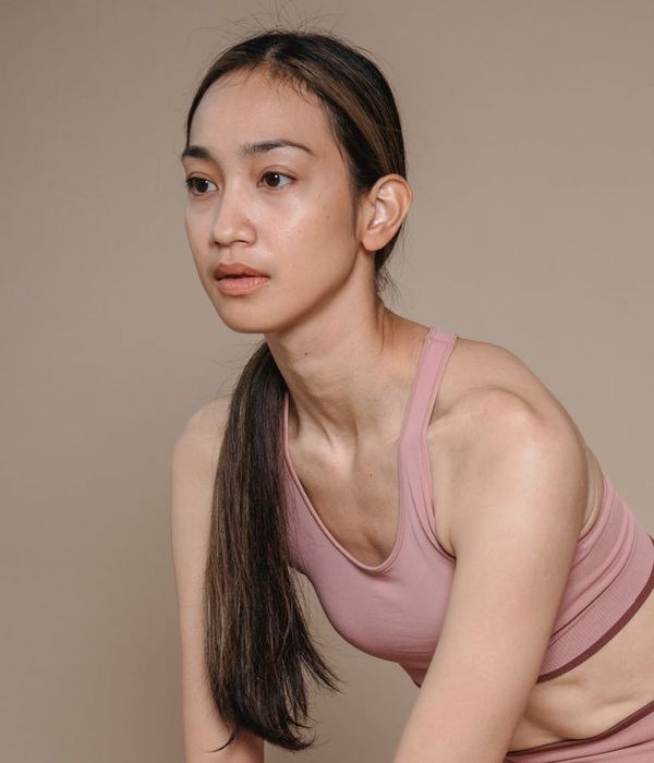 Woman in a calm yoga pose against a dark background with pink accents.